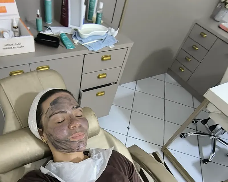 Cliente relaxando com máscara facial na poltrona